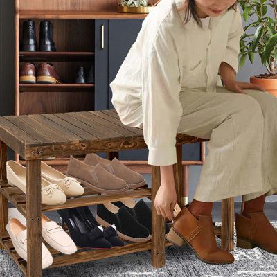 a woman sitting on a wooden bench next to a shoe rack with shoes in it