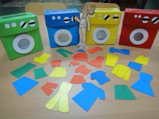 cut out pieces of paper sitting on top of a wooden table next to two toy washing machines