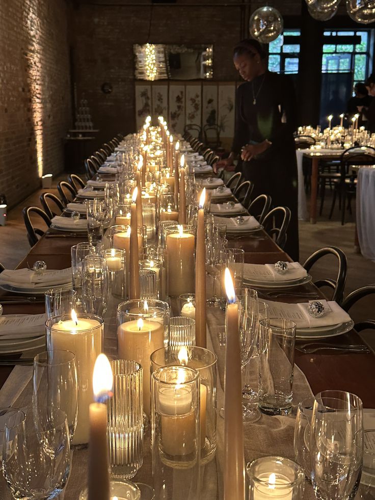 a long table is set with many candles and place settings for dinner guests to enjoy