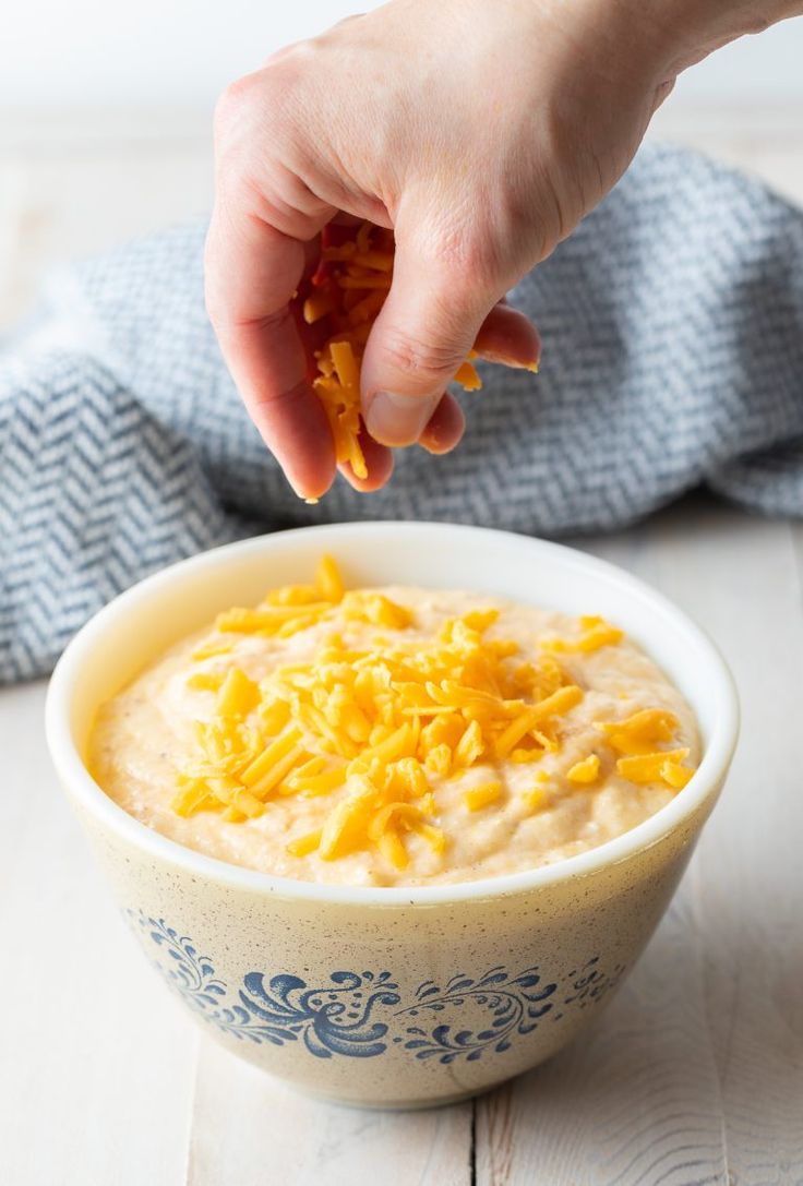 a bowl of oatmeal with orange zest being picked up from it