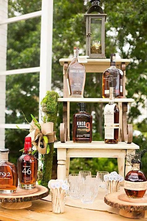 an outdoor table with bottles and glasses on it