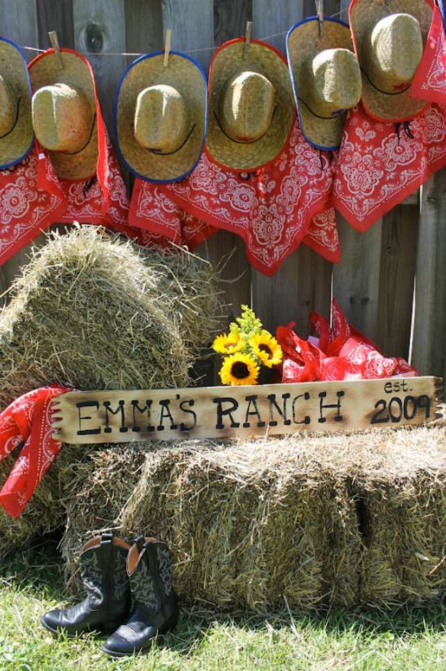 hay bales and hats are arranged in front of a fence with a sign that reads,