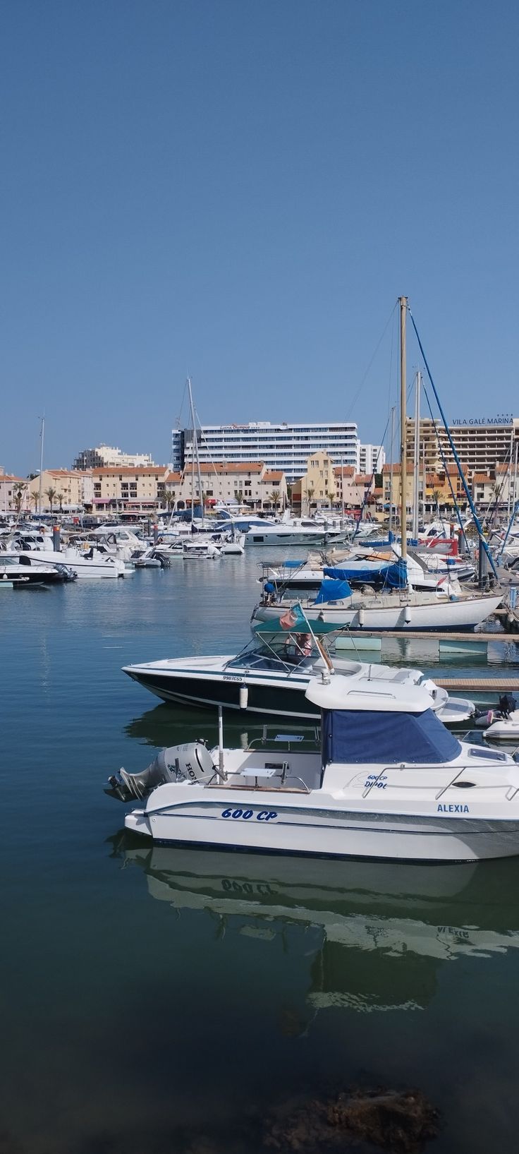 several boats are docked in the water near some buildings and yachts on the shore