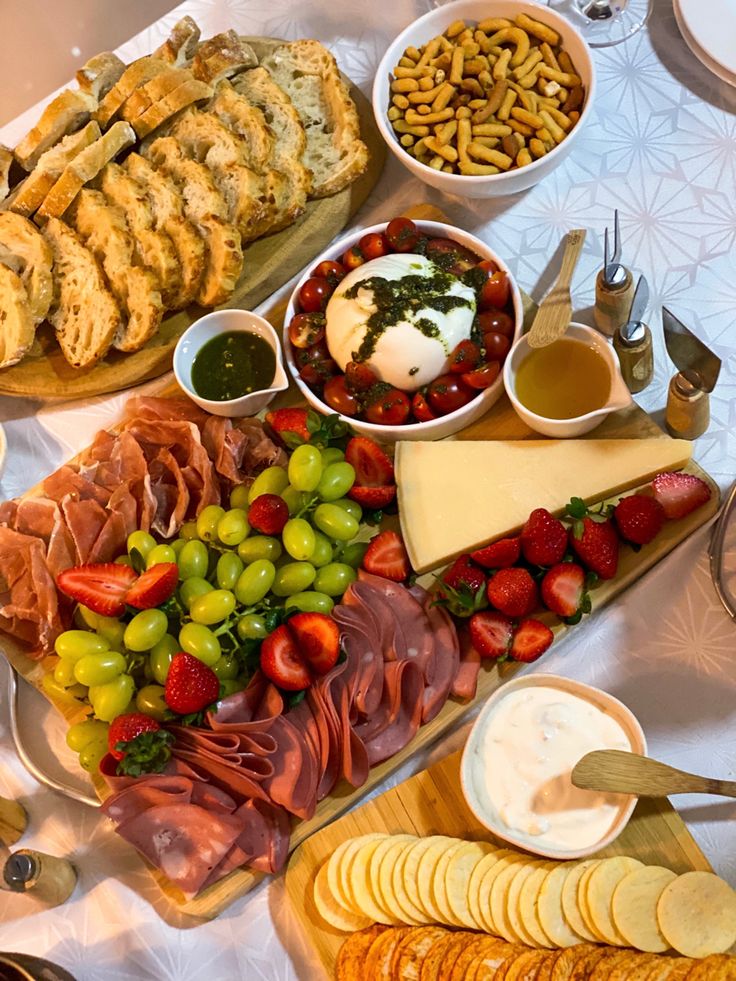 an assortment of cheeses, meats and fruit on a platter with crackers