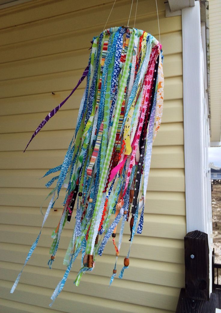 a wind chime hanging from the side of a house with ribbons attached to it