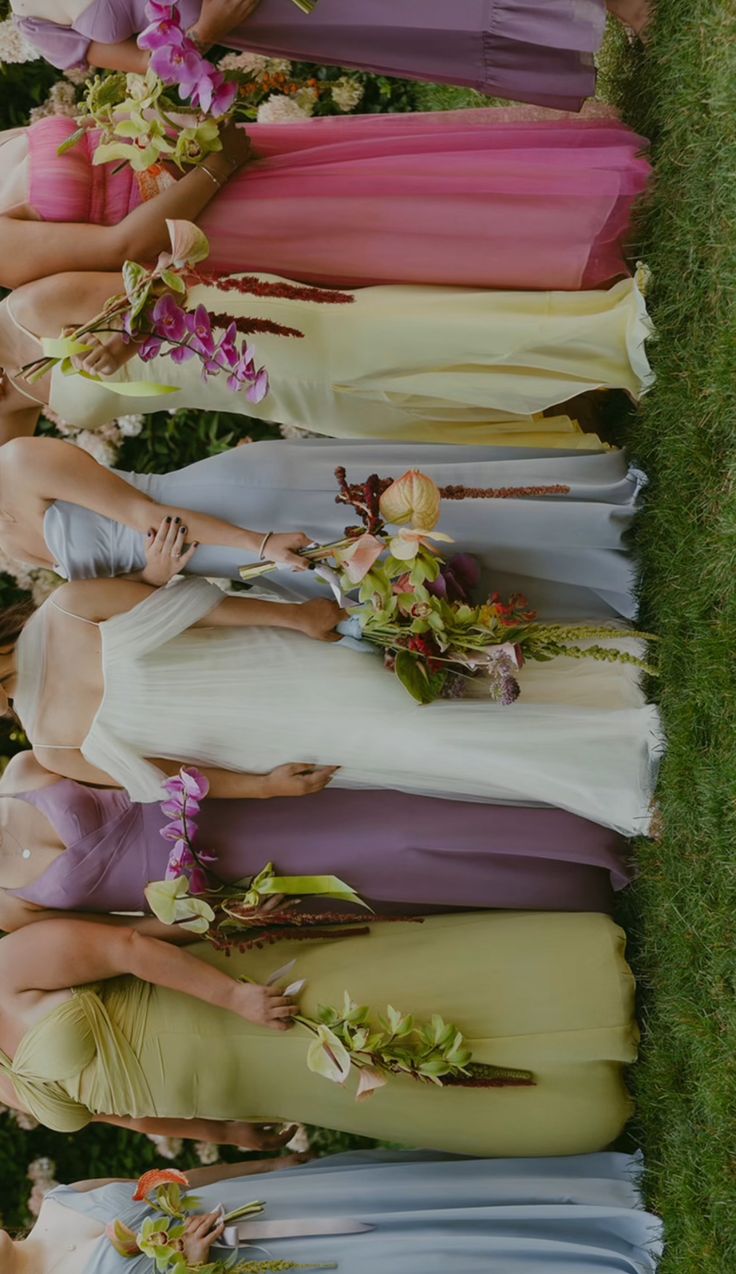 a group of women standing next to each other in long dresses with flowers on them