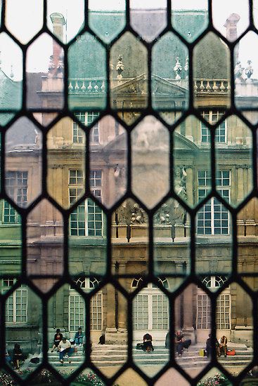 the view from behind a stained glass window shows people walking in front of a building