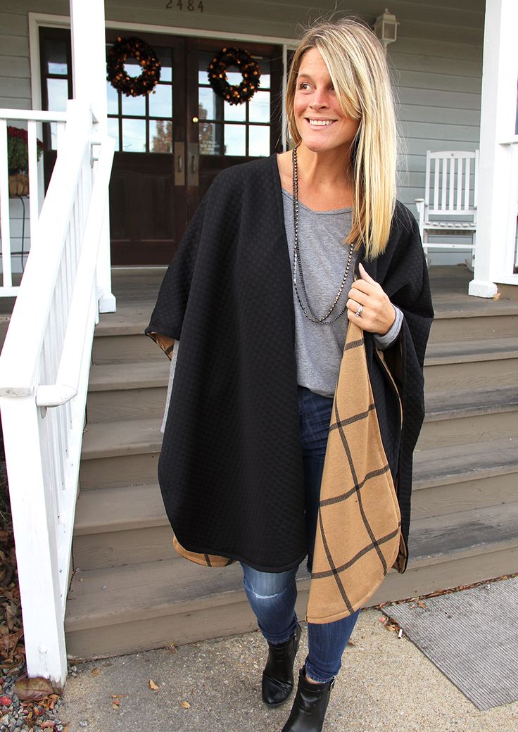 a woman is standing on the steps with a black and tan blanket over her shoulders