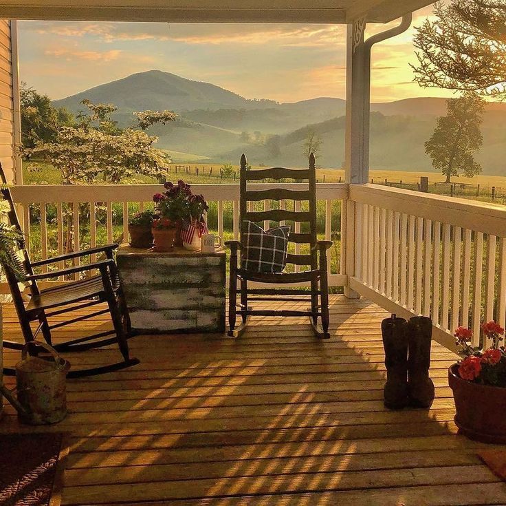 two rocking chairs on a porch with mountains in the background