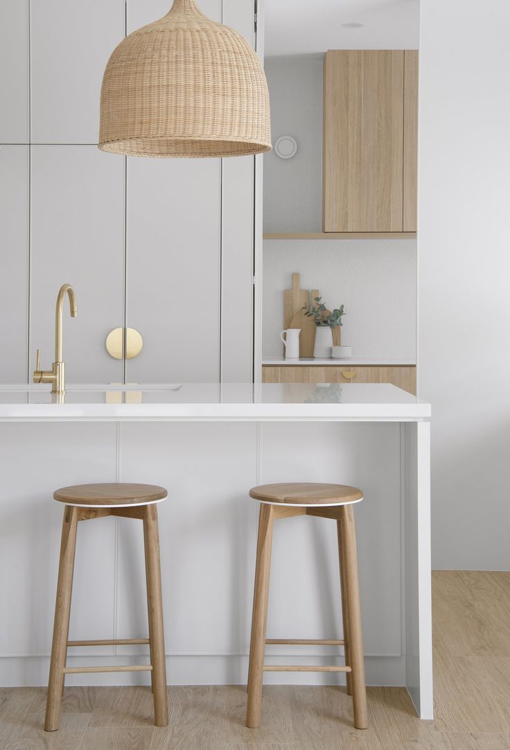 two wooden stools sit in front of an island with a sink and countertop