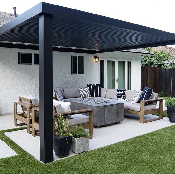 an outdoor living area with couches, tables and potted plants on the grass