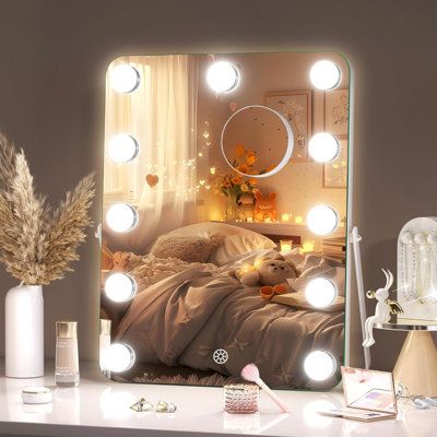 a vanity mirror with lights on top of it next to a vase filled with flowers