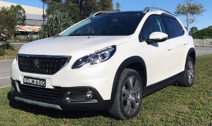 a white car parked on the side of a road in front of trees and grass