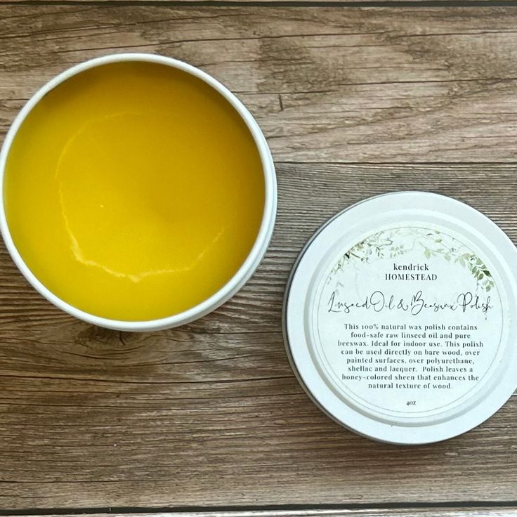 a white bowl filled with yellow liquid next to a container of lip bale on top of a wooden table