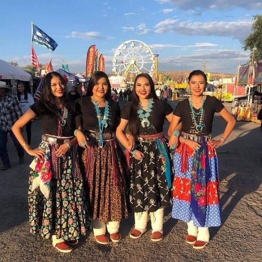 four women are standing in front of an amusement park