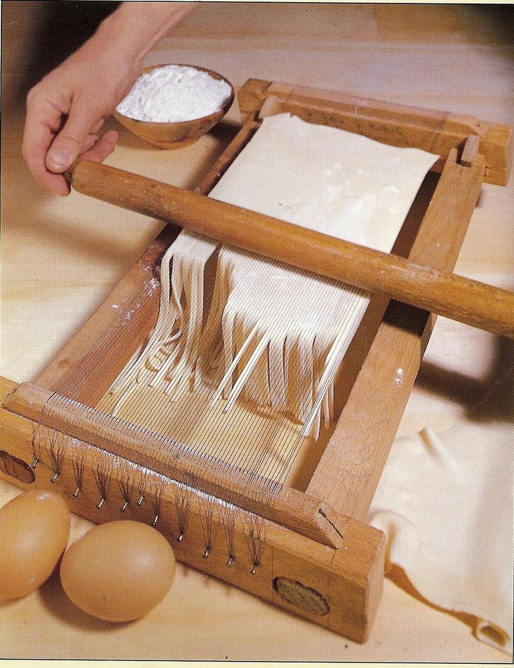 a person is making pasta in an old fashioned wooden box with two eggs on the side