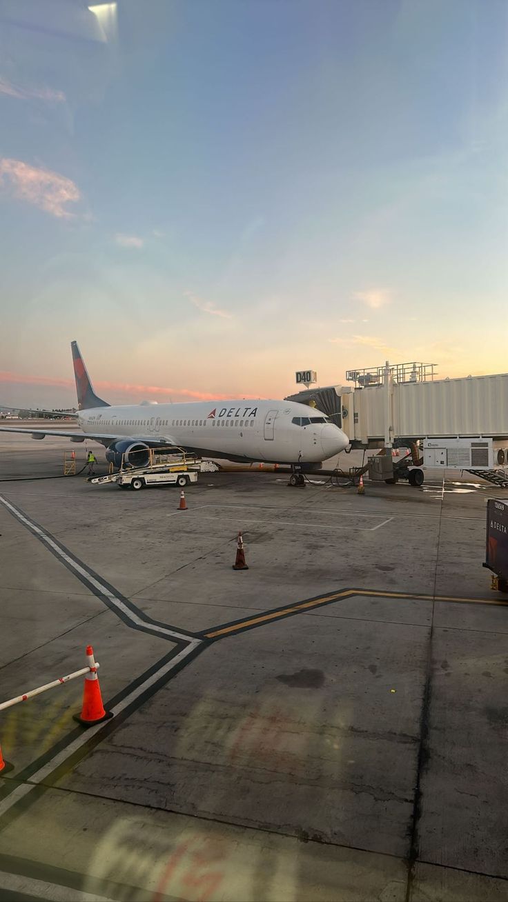 an airplane is parked on the tarmac at sunset