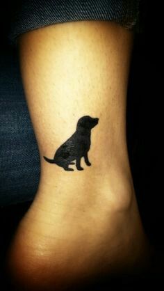 a small black dog tattoo on the side of a woman's leg and foot