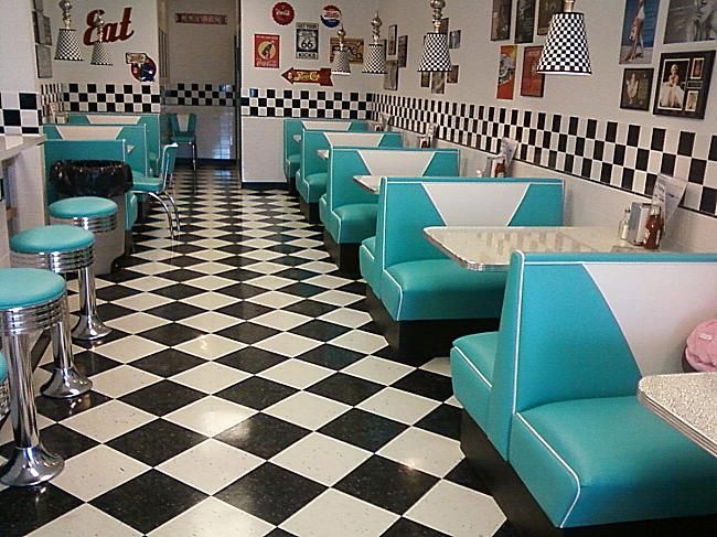 the interior of a diner with checkered flooring and blue booth booths, black and white walls