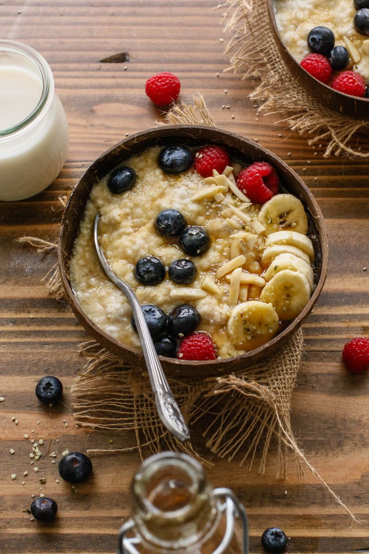 two bowls filled with oatmeal and fruit next to a glass of milk