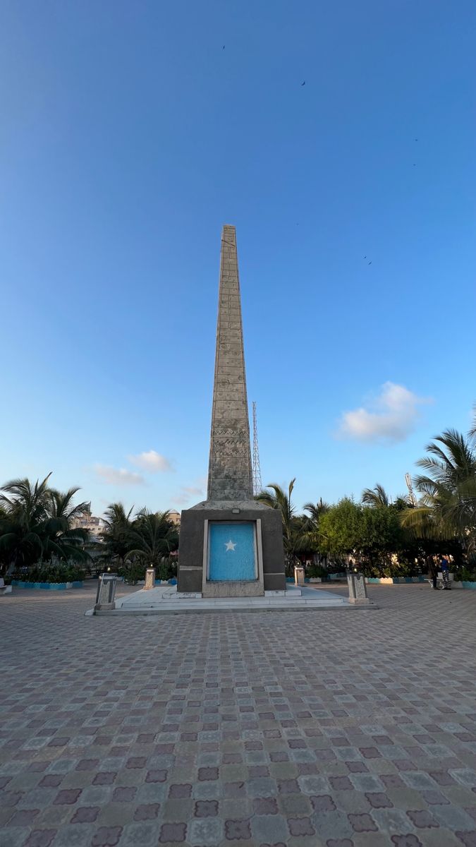 the obelisk stands tall in front of palm trees