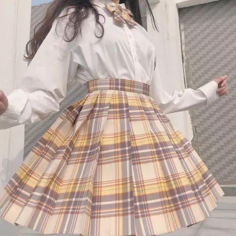 a woman wearing a plaid skirt and white shirt is posing for the camera with her hands on her hips