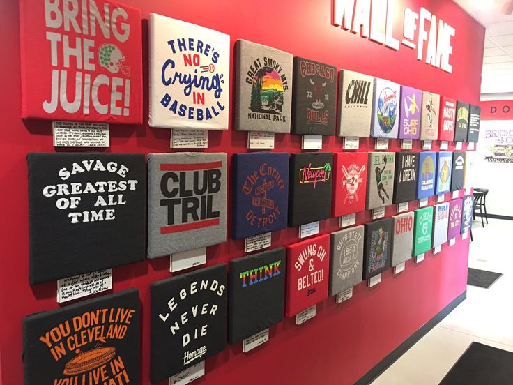 there are many t - shirts hanging on the wall in this office building, and it's time for them to be printed