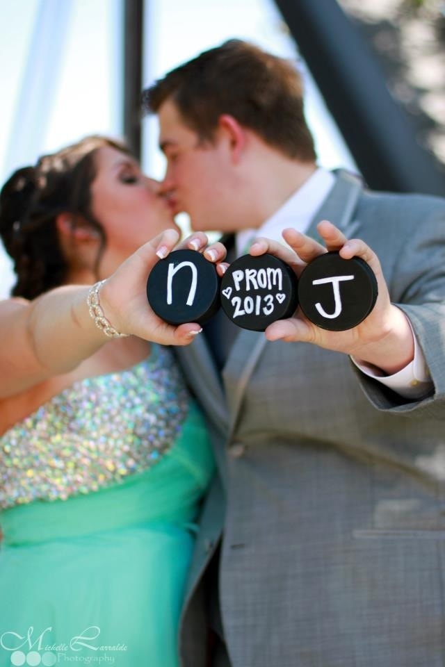 a bride and groom kissing while holding up magnets with the names of their wedding date