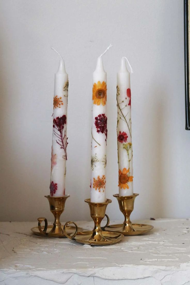 three candles with flowers on them sitting on a table