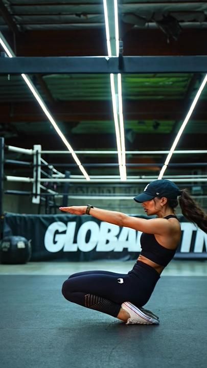 a woman squatting on the ground in a gym