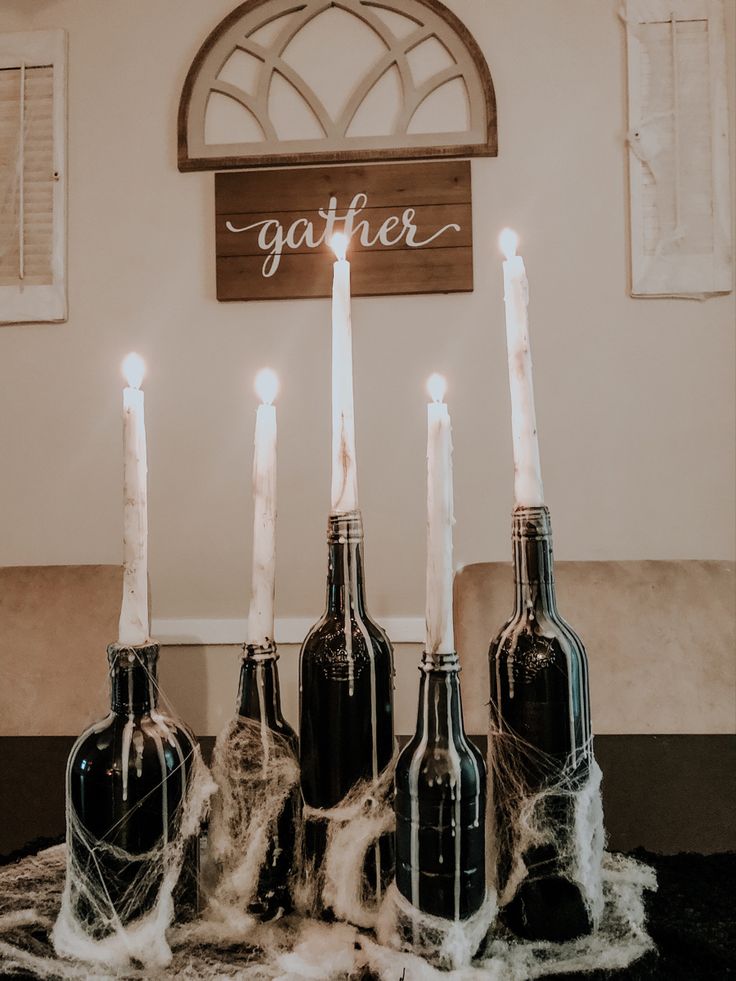 six bottles with candles in them sitting on a table next to a sign that says gather