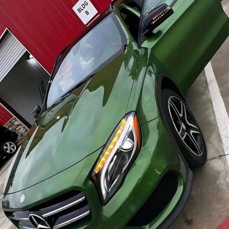 a green car parked in front of a red building