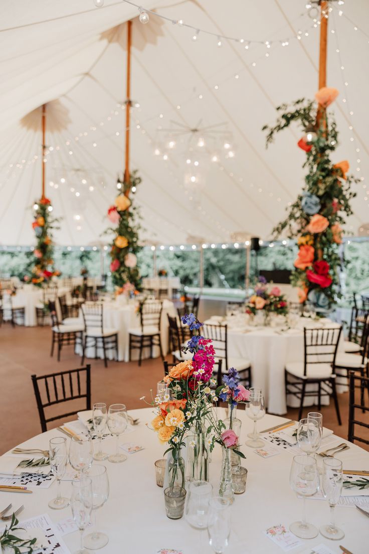 the tables are set up for an event with white linens and floral centerpieces