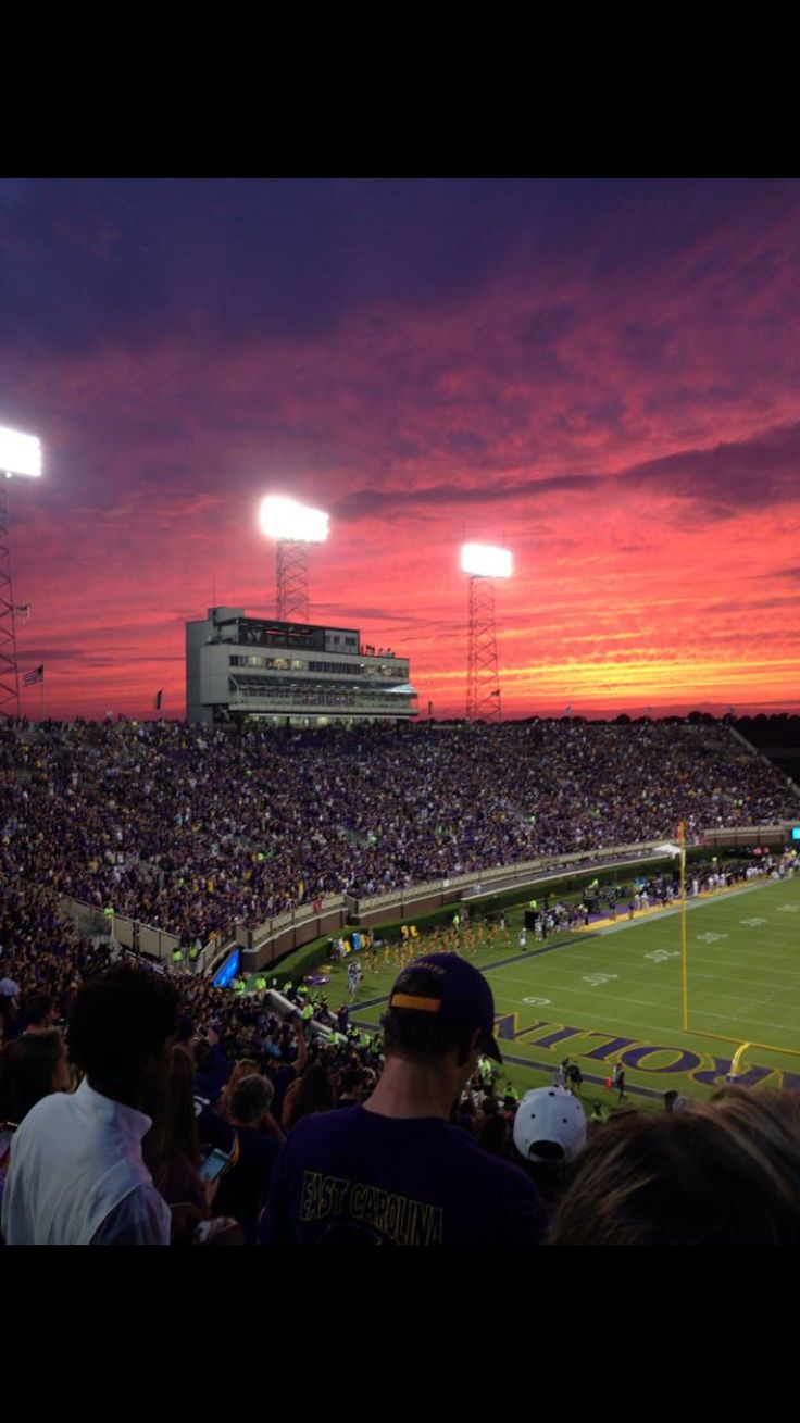 the sun is setting at a football game