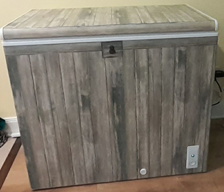 a large wooden box sitting on top of a hard wood floor next to a wall