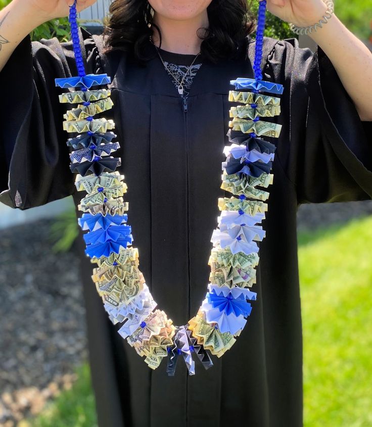 a woman wearing a graduation gown and holding her hands up to her head