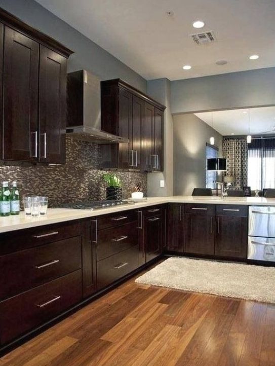 a kitchen with wooden floors and dark cabinets