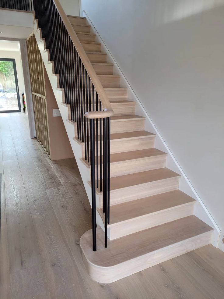 the stairs are made of wood and have black railings on each handrail, along with a white painted wall