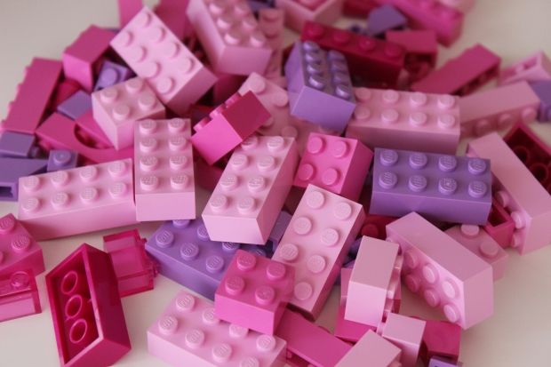 a pile of pink and purple legos sitting on top of a white table next to each other