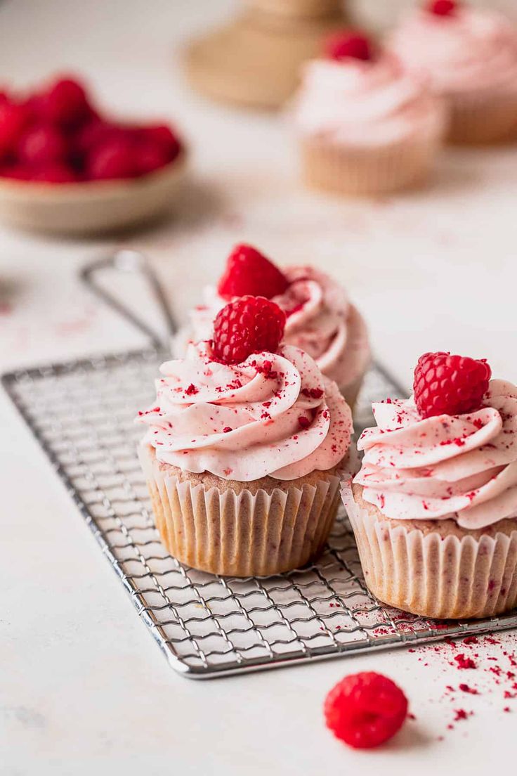 two raspberry cupcakes on a cooling rack