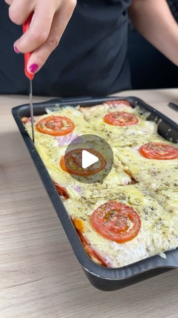 a woman is cutting up some food in a pan with a knife on the table