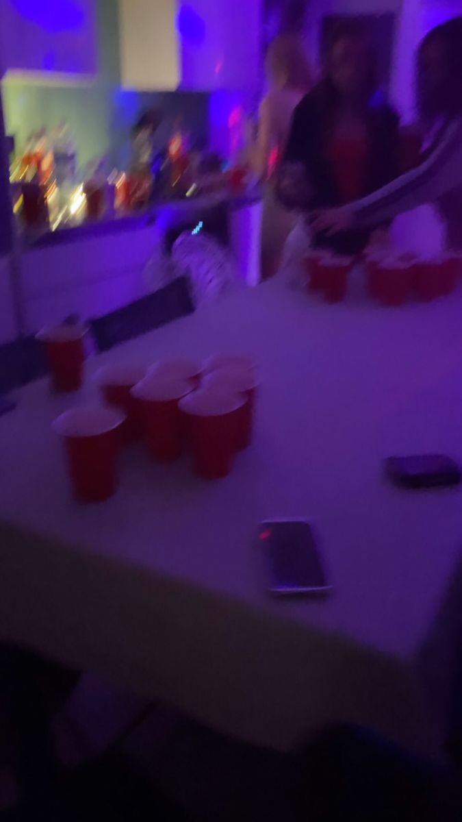 some people are sitting at a table with red cups and cell phones on the table