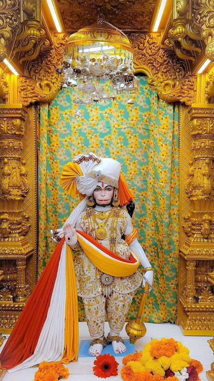 a person dressed in an elaborate costume and holding a large orange bag next to flowers