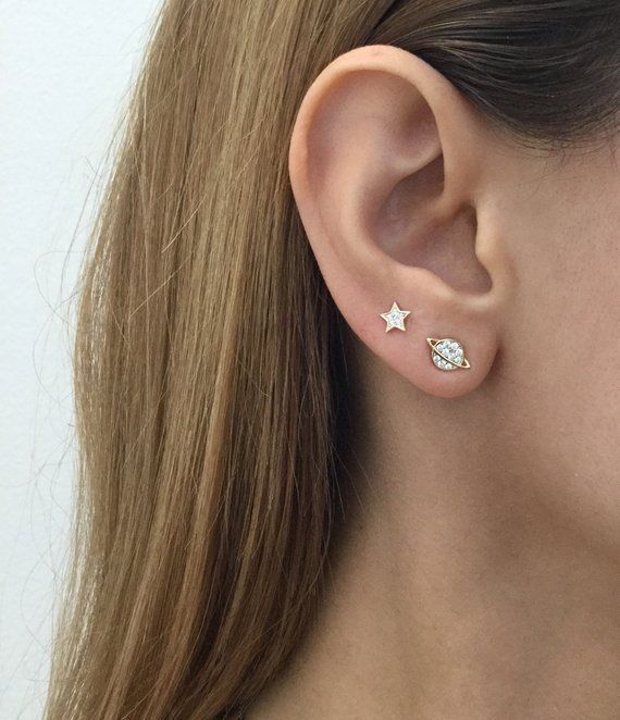 a close up of a person's ear wearing a pair of star and diamond earrings