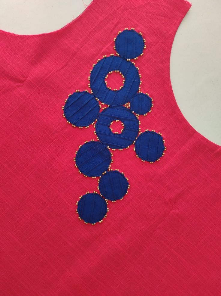 the back of a pink top with blue circles on it and beaded trims