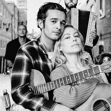 a man holding a guitar next to a woman