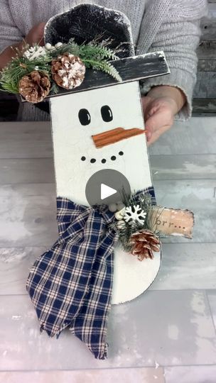 a snowman made out of wood with pine cones on its head and plaid bow