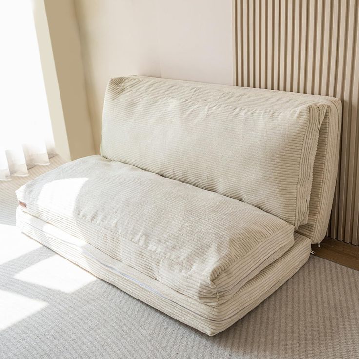 a white couch sitting on top of a rug next to a wall mounted radiator