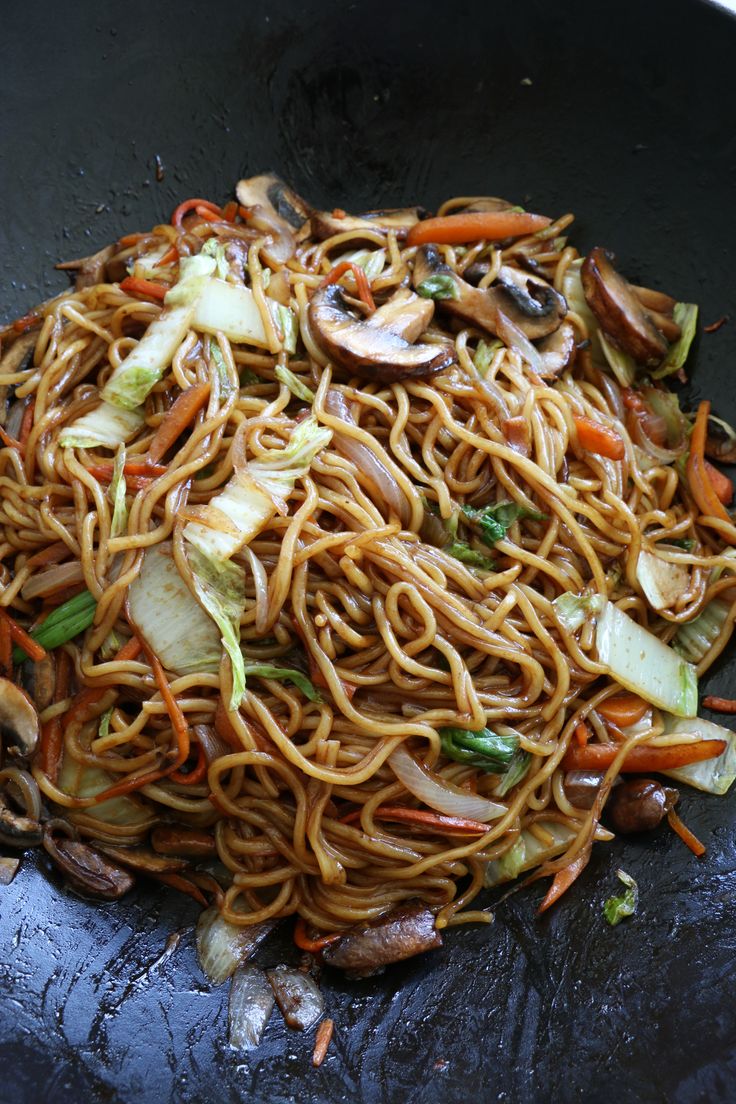 noodles and vegetables are being cooked in a wok