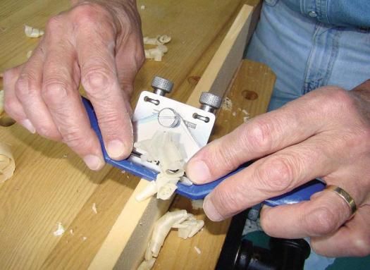 two hands are working on an object in the process of making something out of wood